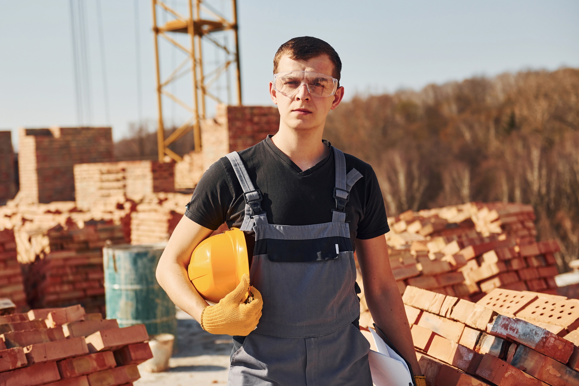 Portrait of construction worker in uniform and safety equipment that stands on rooftop