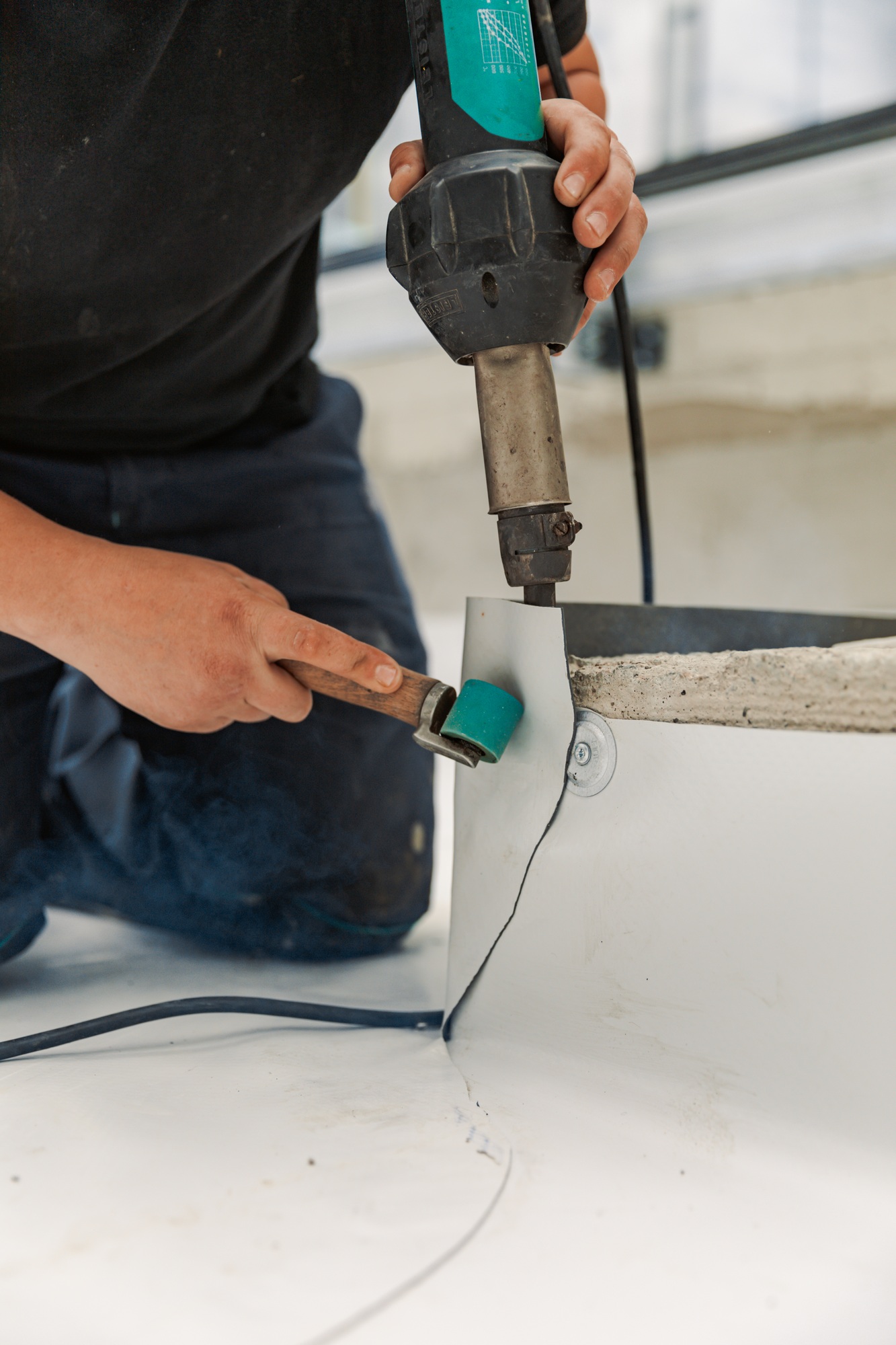 Worker welding pvc membrane by heater with welder machine