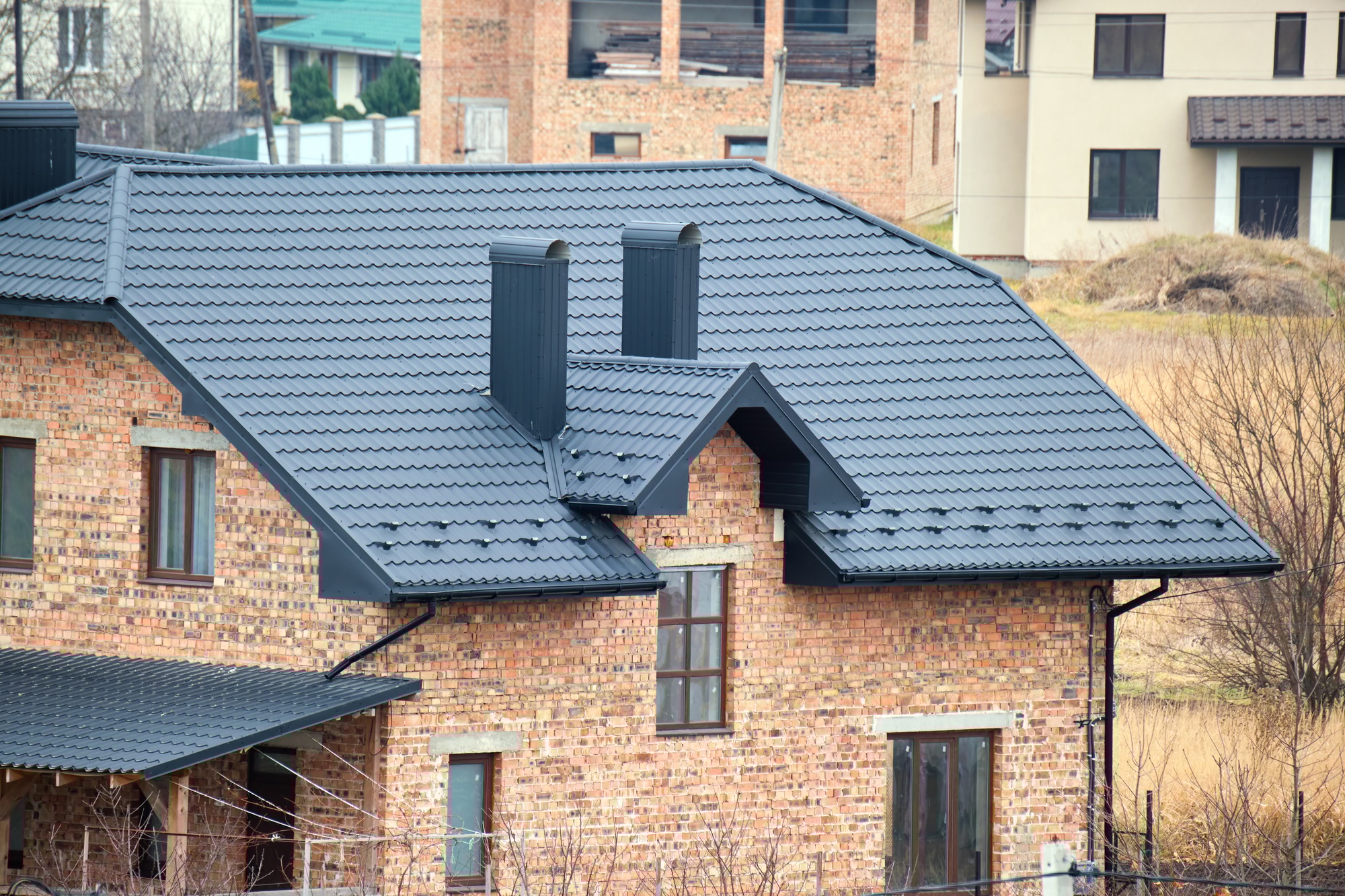 Chimney on house roof top covered with metallic shingles under construction